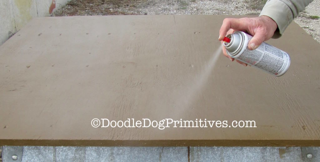 spraying varnish on back of barn quilt